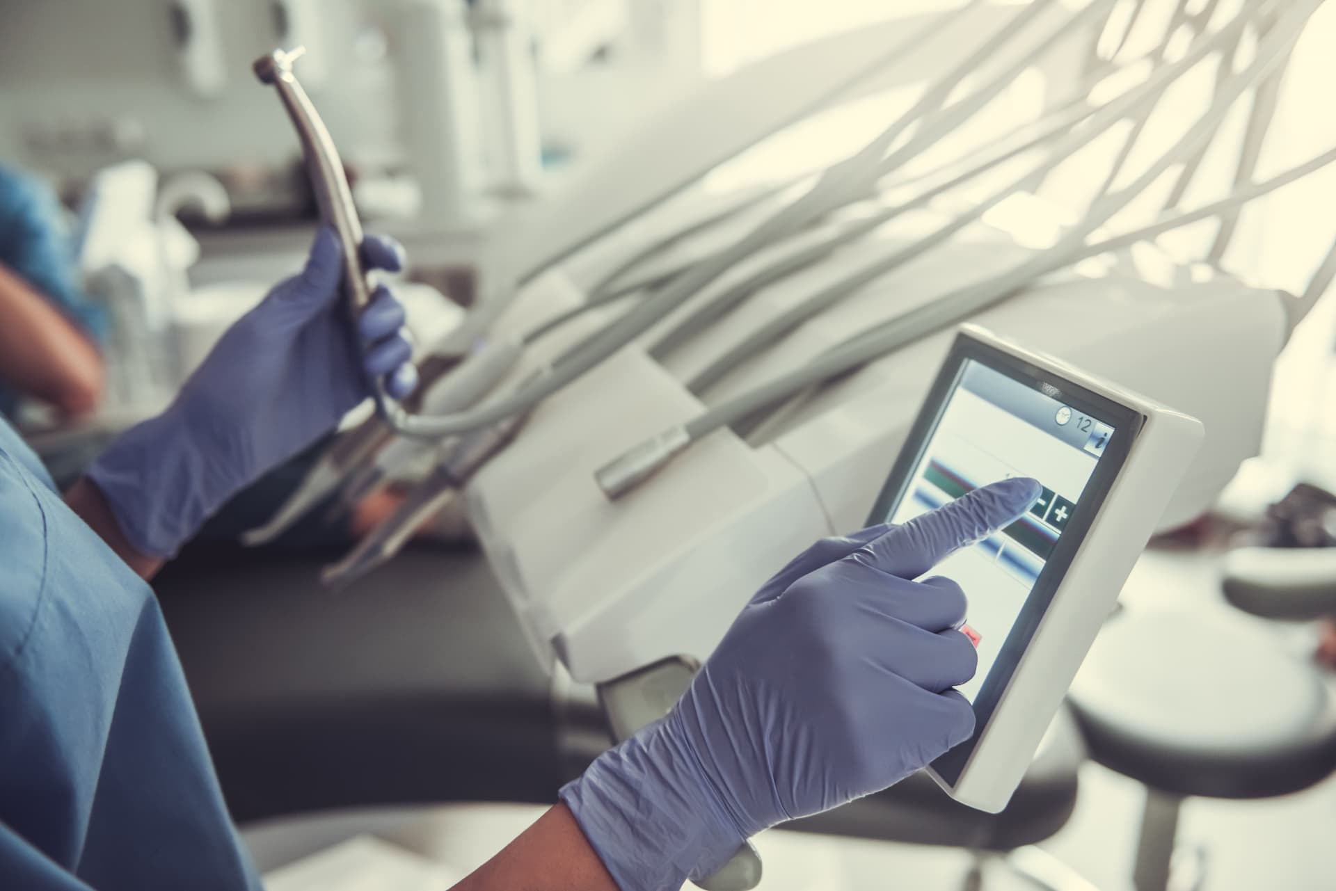 Dentist adjusting settings on modern dental equipment